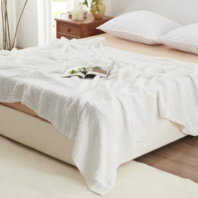 Love's Cabin 100% cotton muslin blanket on bed for breathable warmth.