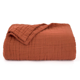 Love's cabin orange-hued muslin blanket—vibrant accent on your sofa.
