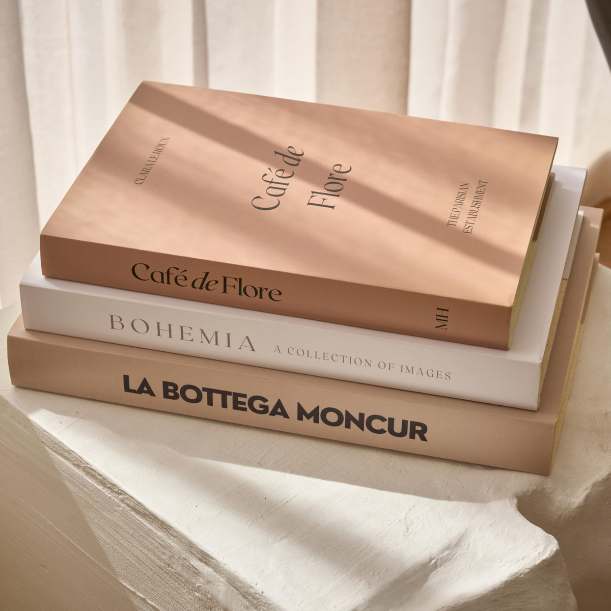 Moncur Home faux books with beige and white covers elevate coffee table styling.