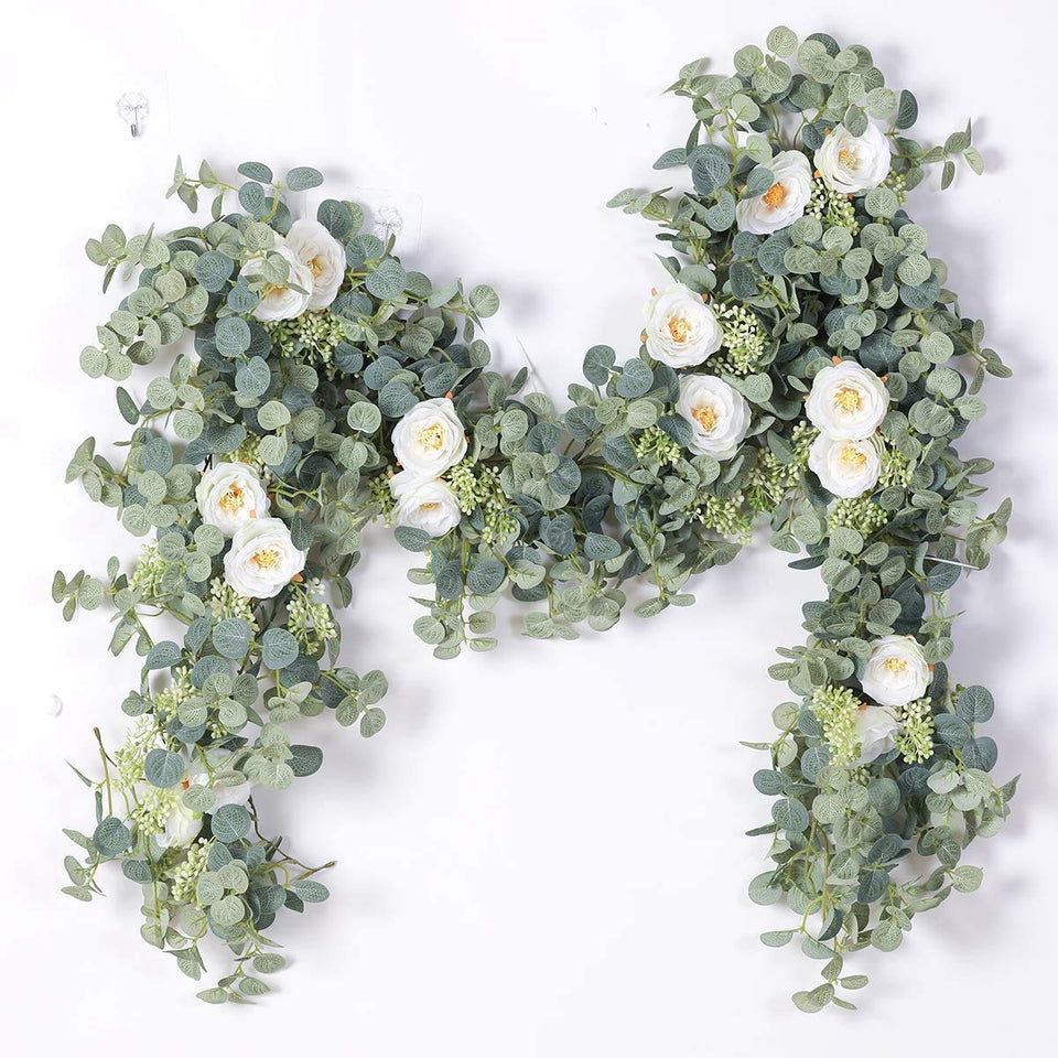 Party Joy eucalyptus garland with eight white roses on a backdrop for wedding styling