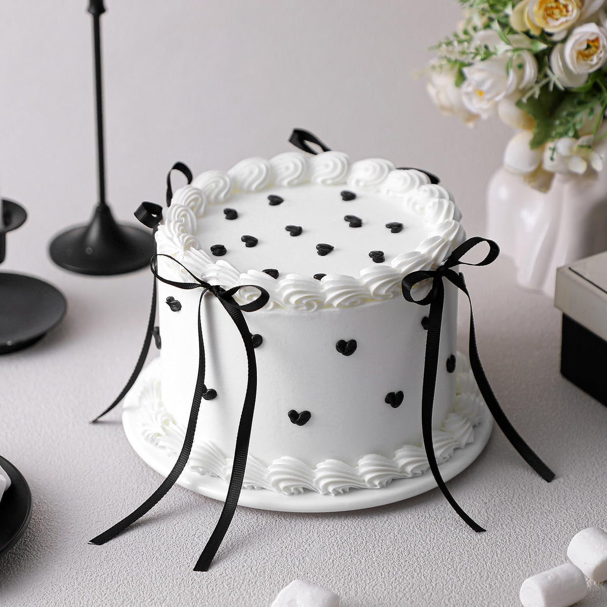 Remerry 6-Inch black bow white round fake cake on a display table for wedding decor.