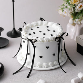 Remerry 6-Inch black bow white round fake cake on a display table for wedding decor.