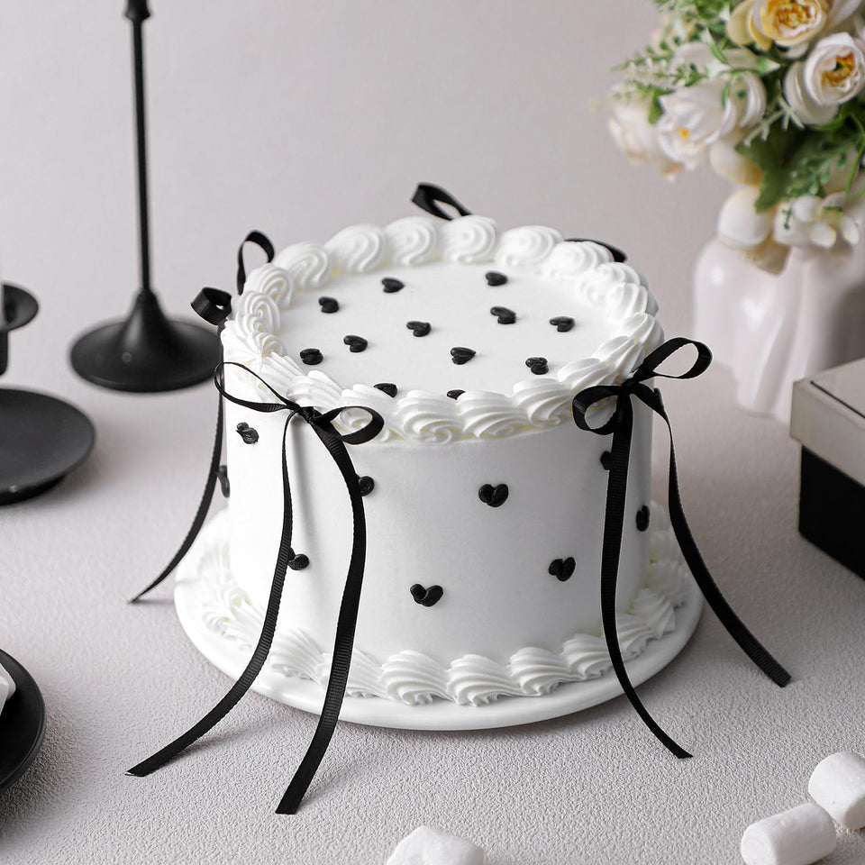 Remerry 6-Inch black bow white round fake cake on a display table for wedding decor.