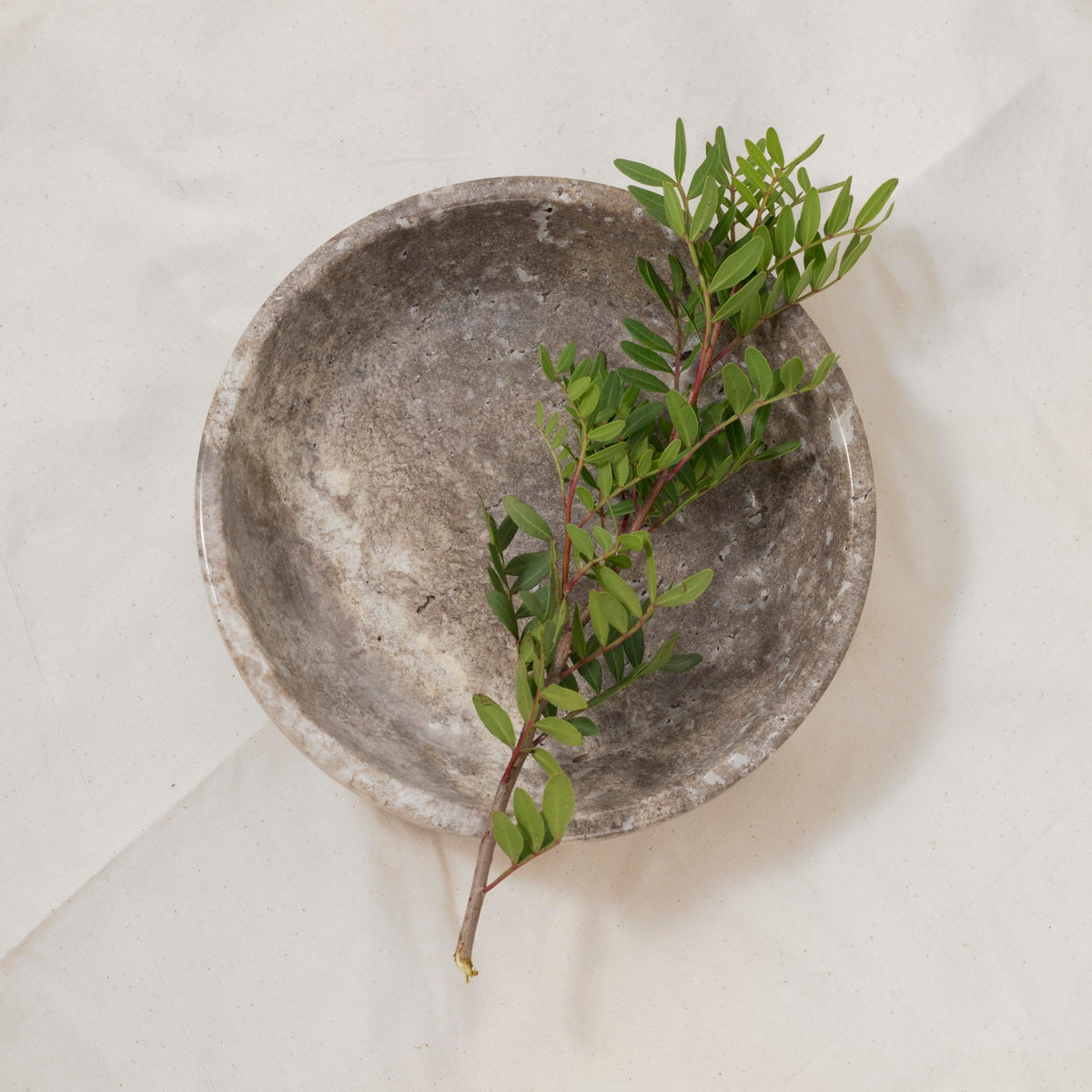 Shelf & Nook travertine bowl in natural ivory on a coffee table