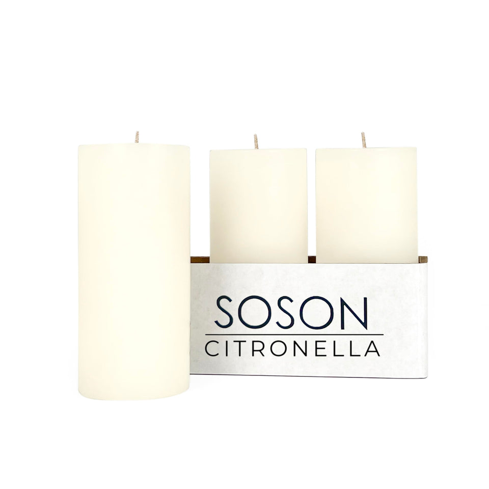 Simply Soson citronella candle ivory pillar glows on a patio table for outdoor dining.