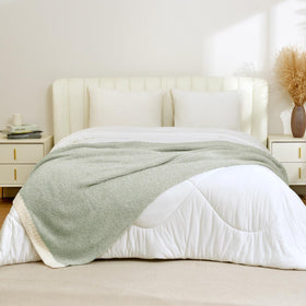 Sage green Snuggle Sac throw across a bed for warmth and decor.