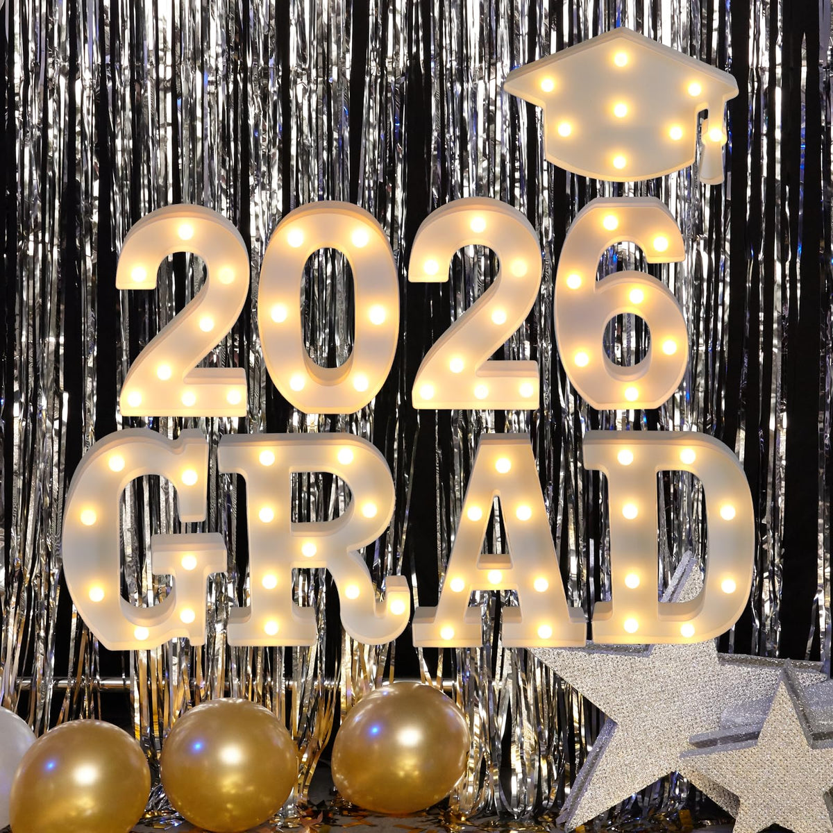 Suyeah Grad 2026 letters glow on desk, brightening graduation photo backdrop.