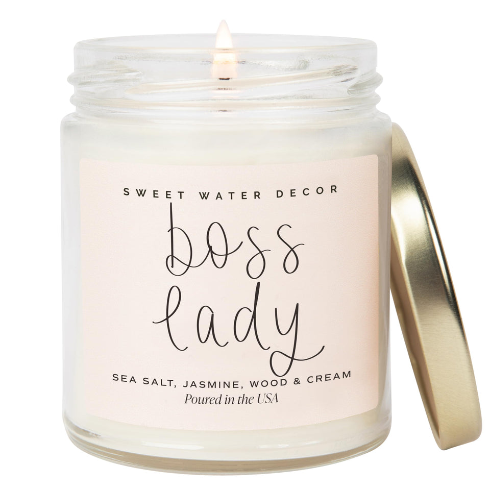 Sweet Water Decor Boss Lady Candle in a clear jar on a stylish desk.