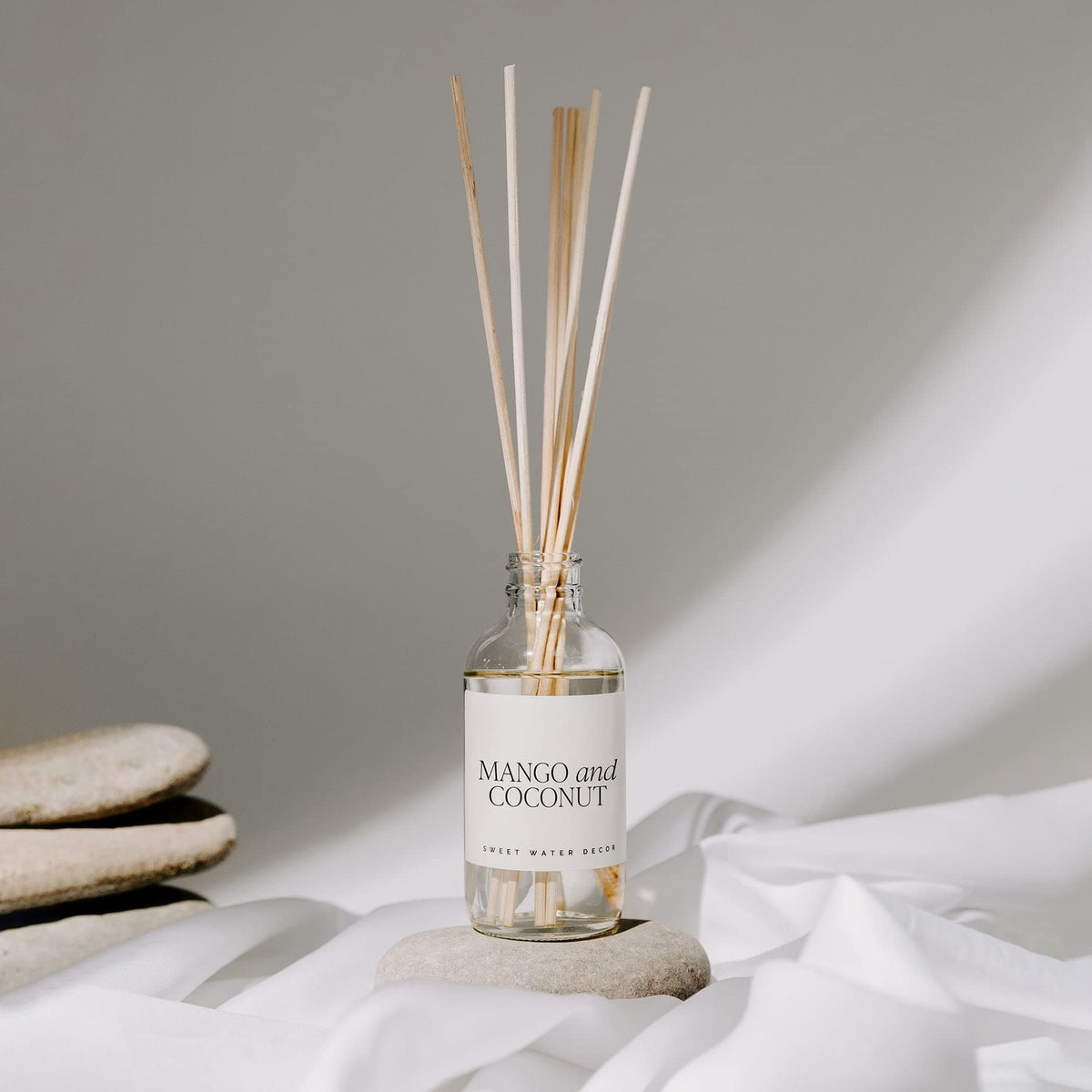 Sweet Water Decor mango-orange diffuser bottle on a coffee table for everyday freshness.