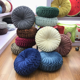 Teieas pleated round cushion offers elegant support for lounging at home.
