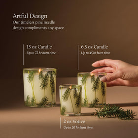 Thymes Frasier Fir candle in a clear glass jar with pine needle motif for festive decor.