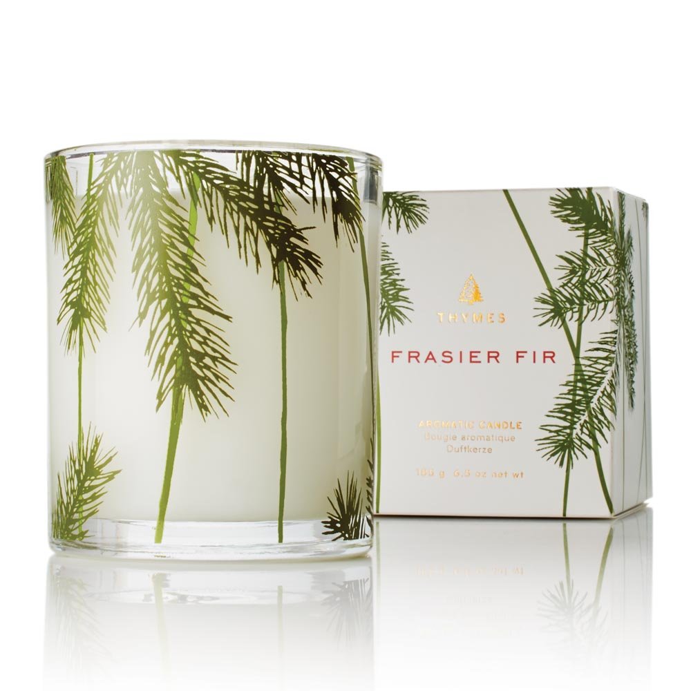 Thymes Frasier Fir Pine Needle Candle in a 6.5 oz jar creating a cozy winter ambiance.