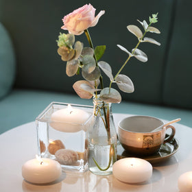 Tuyai candles glimmer in a pool or water feature for ambiance.