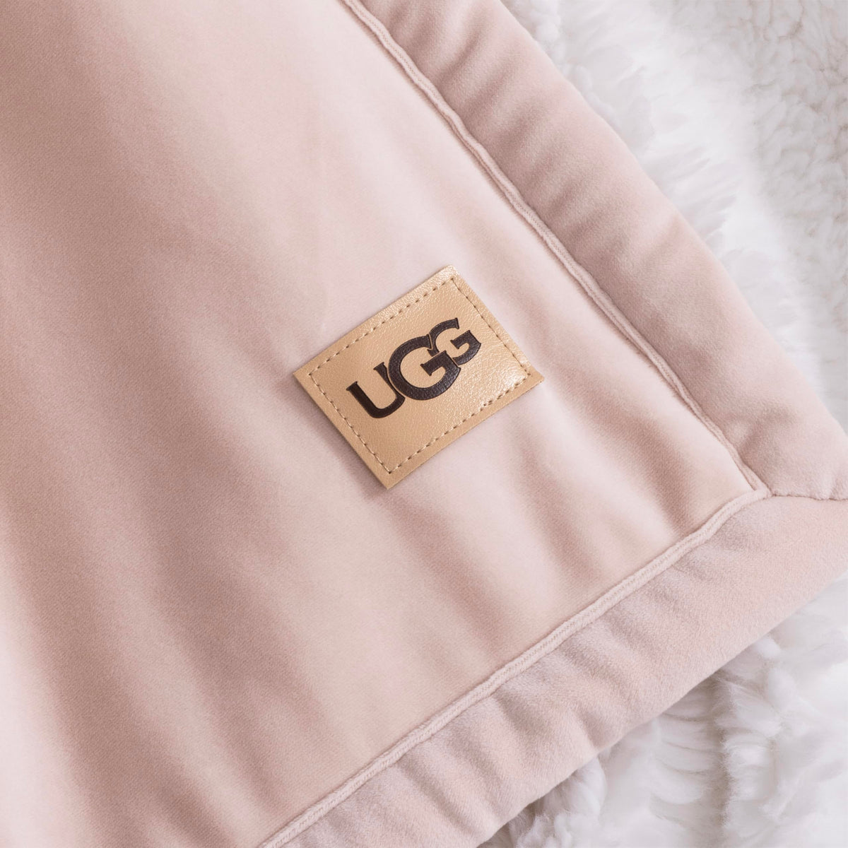 UGG Bliss Throw Blanket care label close-up shows machine wash instructions.