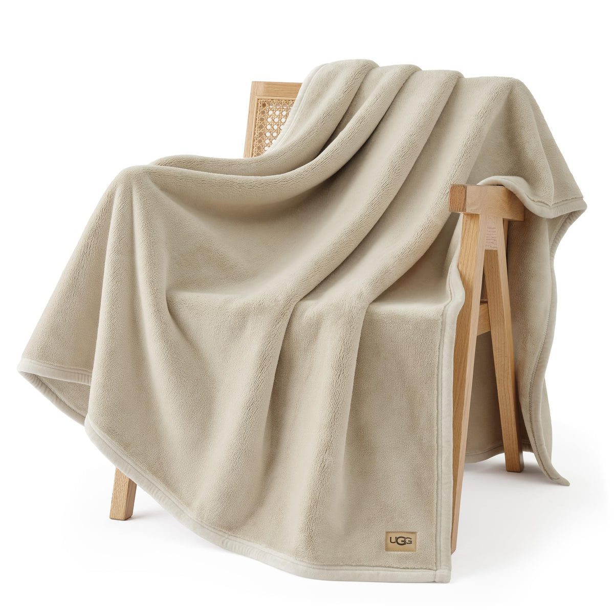 UGG Coco throw blanket in ivory on sofa shows plush warmth for cozy evenings.