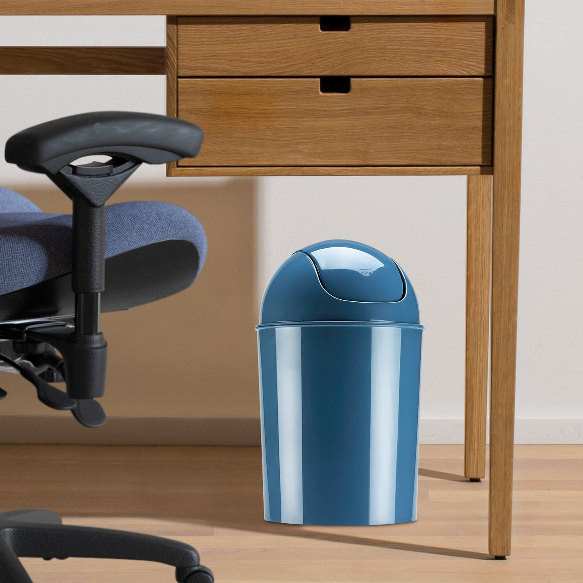 Umbra mini waste can in mist blue placed under counter for space-saving trash