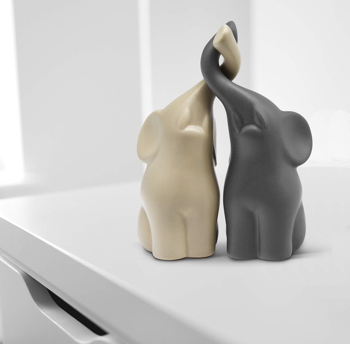 Vaudagio elephants in love beige-grey figurine highlights a connection symbol on a mantel.