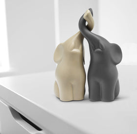 Vaudagio elephants in love beige-grey figurine highlights a connection symbol on a mantel.