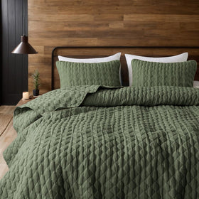 WDCOZY olive green quilt folded beside two shams on bed