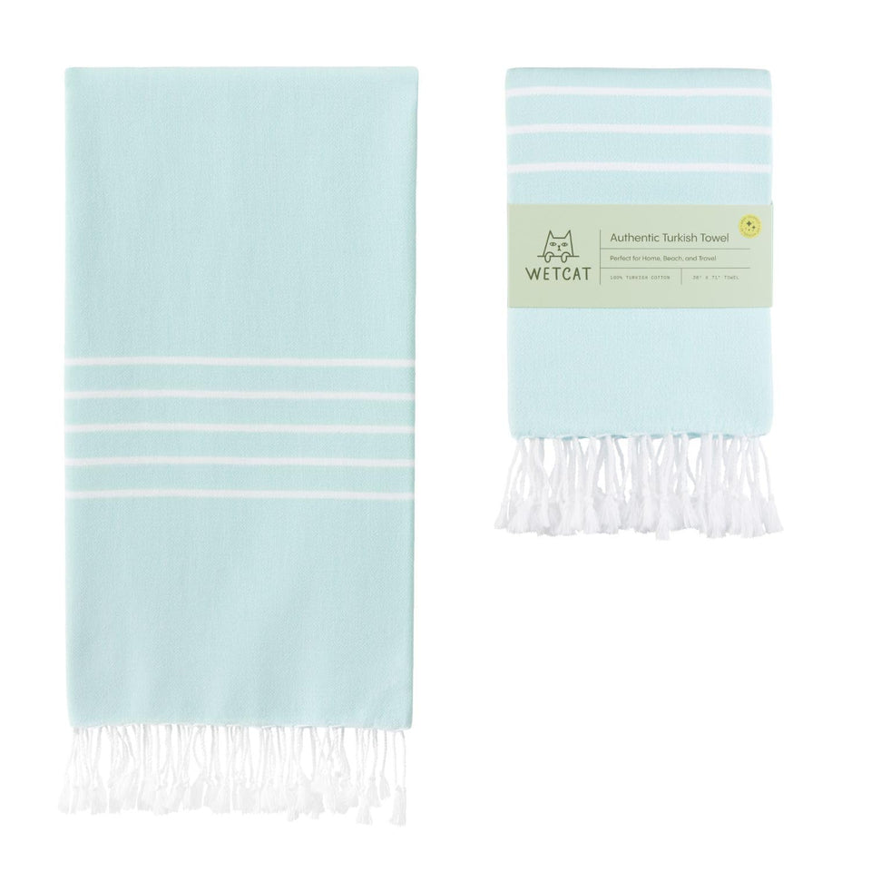 WetCat Turkish Beach Towel Aquamarine oversized 38x71 laid out on sand.