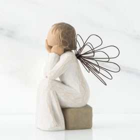 Willow Tree Angel of Caring seated on gray rock for a tranquil display.
