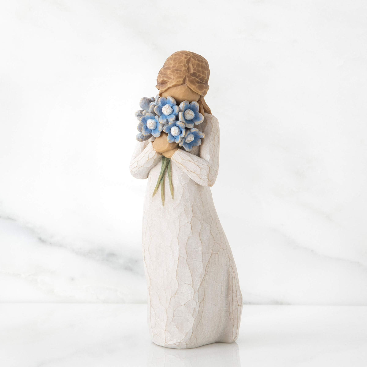 Willow Tree Forget-me-not blue bouquet up to her face, creates a tender sympathy mood