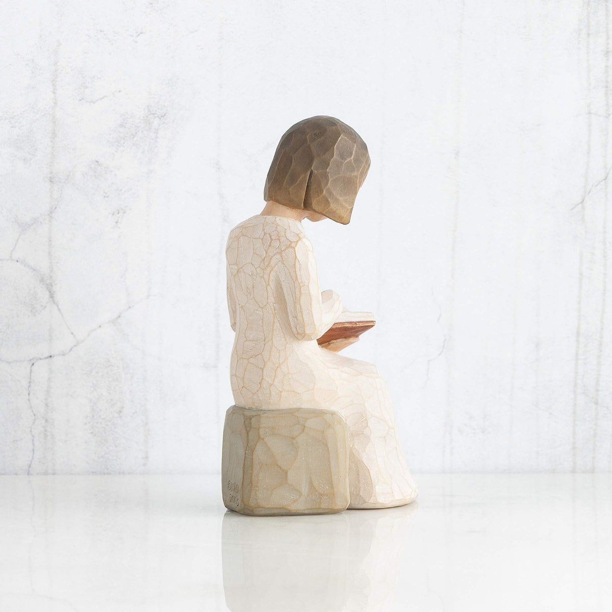 Willow Tree Wisdom figure on a mantel with gray rock display.