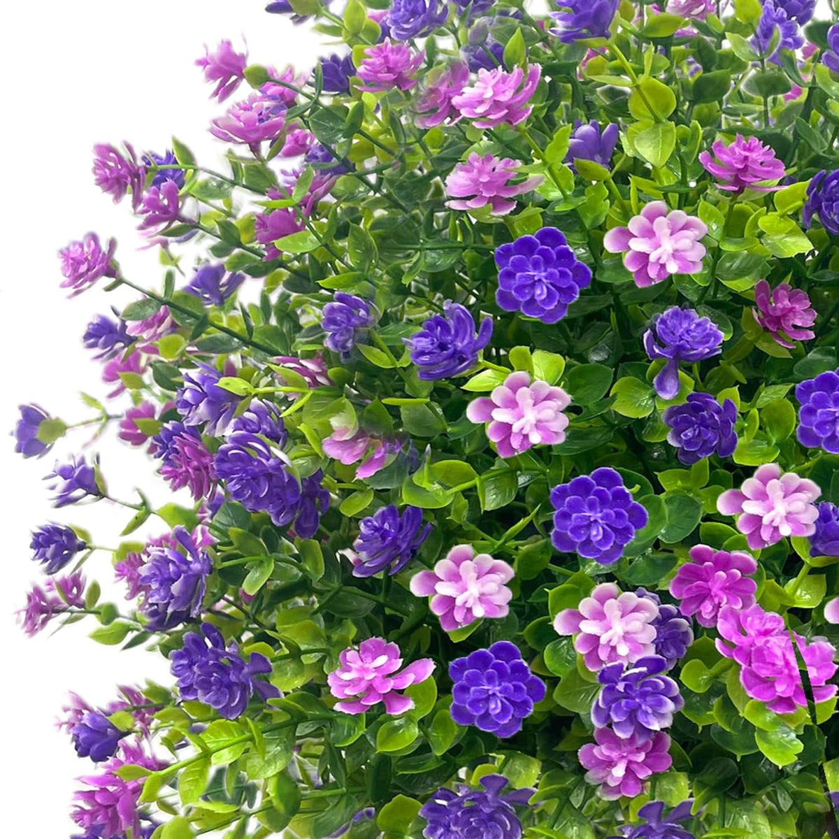 Close-up of YUGYUM topiary showing purple silk flowers and green foliage.